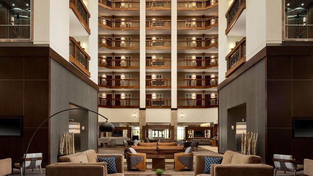 A spacious lobby with a central seating area, multiple floors of balconies, and a modern design. - Minneapolis Marriott Northwest Hotel & Conference Center (Brooklyn Park)