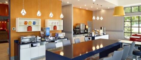 Une cuisine moderne dotée d’un îlot central, de tabourets de bar, de luminaires suspendus et offrant une vue sur l’extérieur.