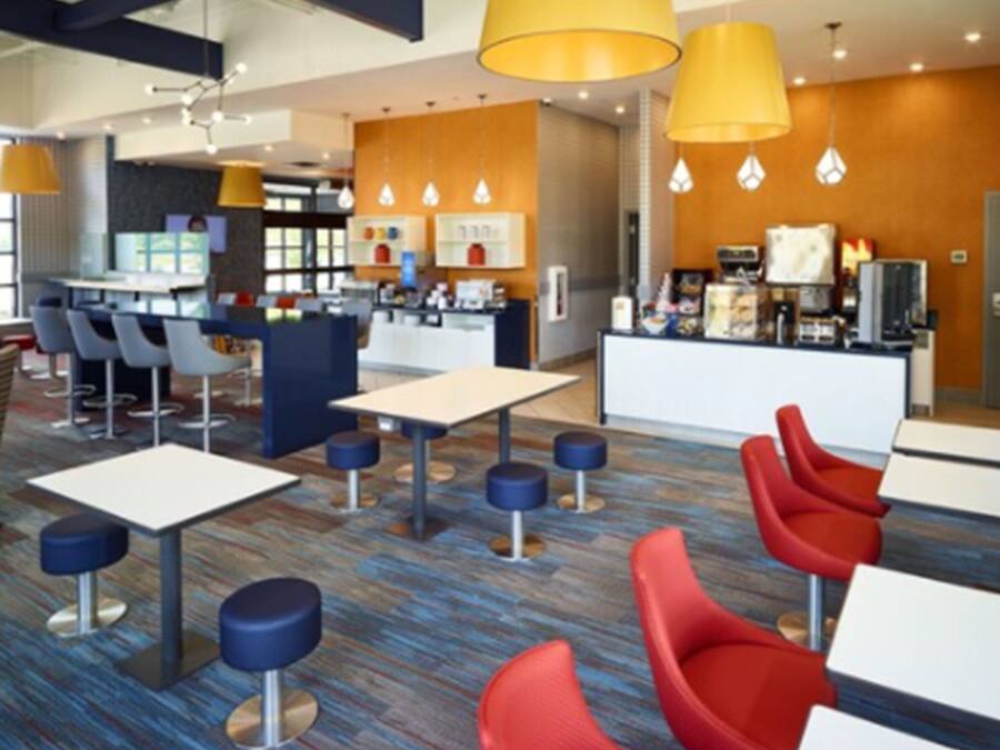 Um lobby de hotel moderno com área de bar, assentos e balcão de recepção.