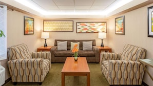 A hotel room with a sofa set, two armchairs, a wooden coffee table, and a patterned carpet. - La Quinta Inn by Wyndham Minneapolis Airport Bloomington (Bloomington)