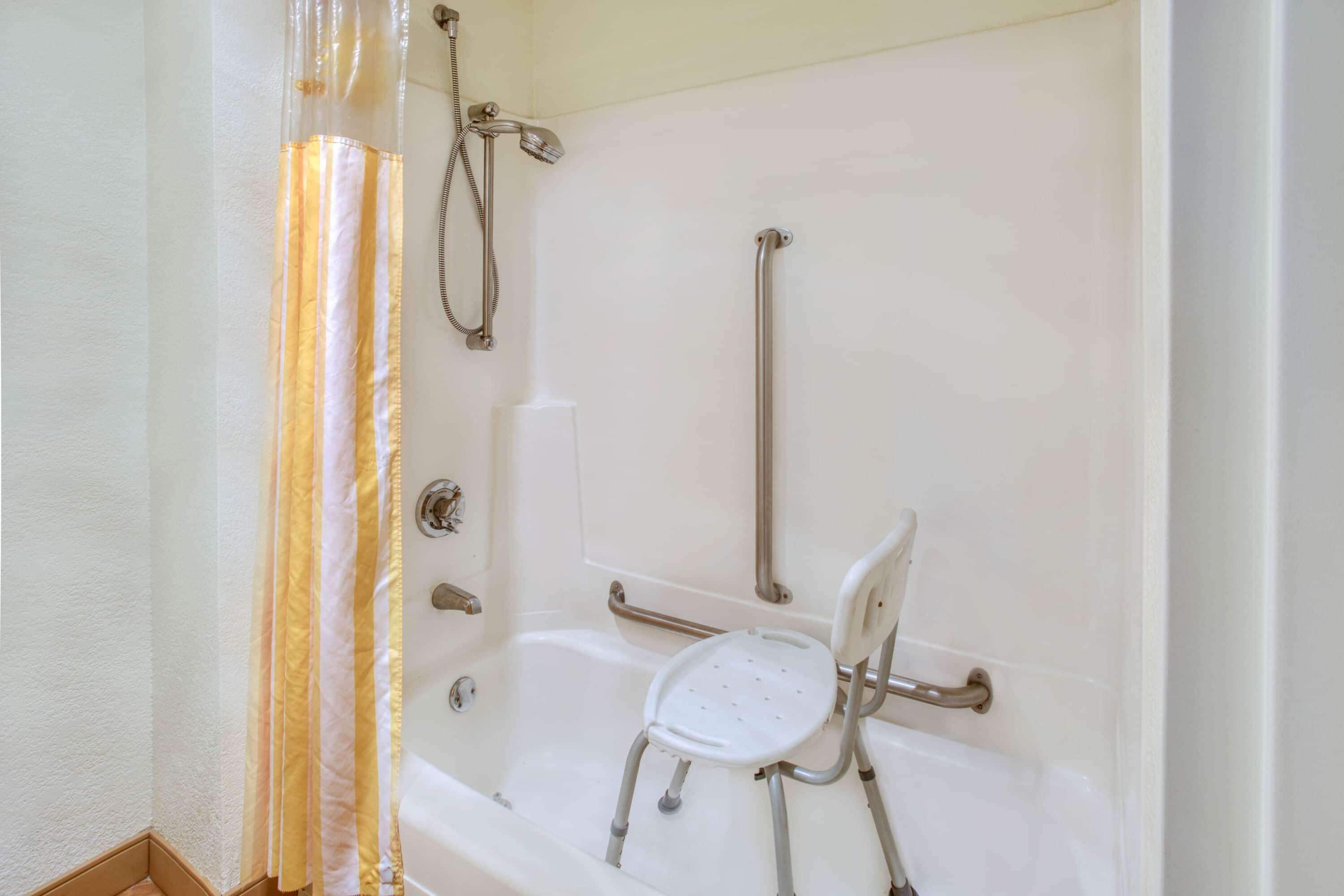 Une salle de bain équipée d’une baignoire, d’une douche et d’une barre d’appui.