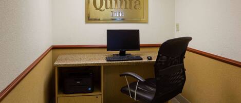 A hotel room with a desk, computer, and chair.