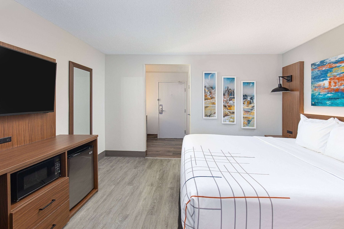 A hotel room with a bed, a TV, a microwave, and a small kitchenette.