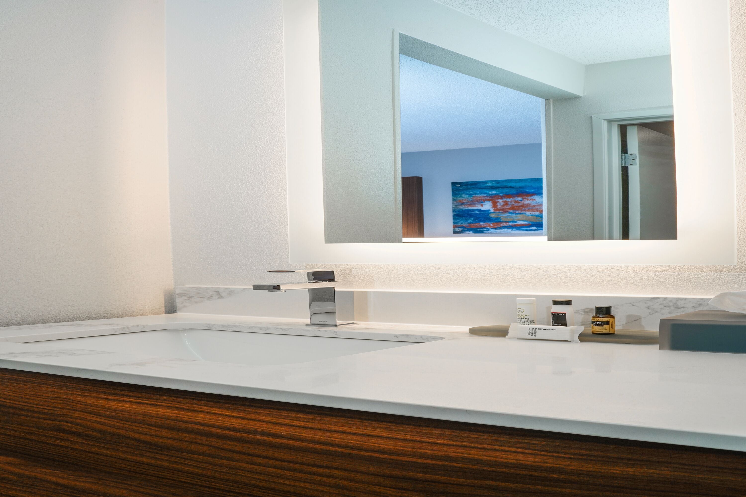 A bathroom with a white sink, a large mirror, and a wooden vanity.