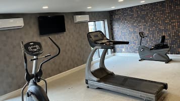 A hotel fitness room with a treadmill, stationary bike, and a wall-mounted TV.