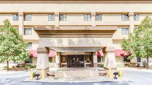 A multi-story hotel entrance with a covered entryway, a fire lane sign, and a security camera.