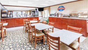 A breakfast area with tables, chairs, a coffee station, and a sign for 'Baymont Breakfast Corner.'
