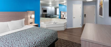 A hotel room with a large bed, a separate bathroom with a bathtub, and a desk area.