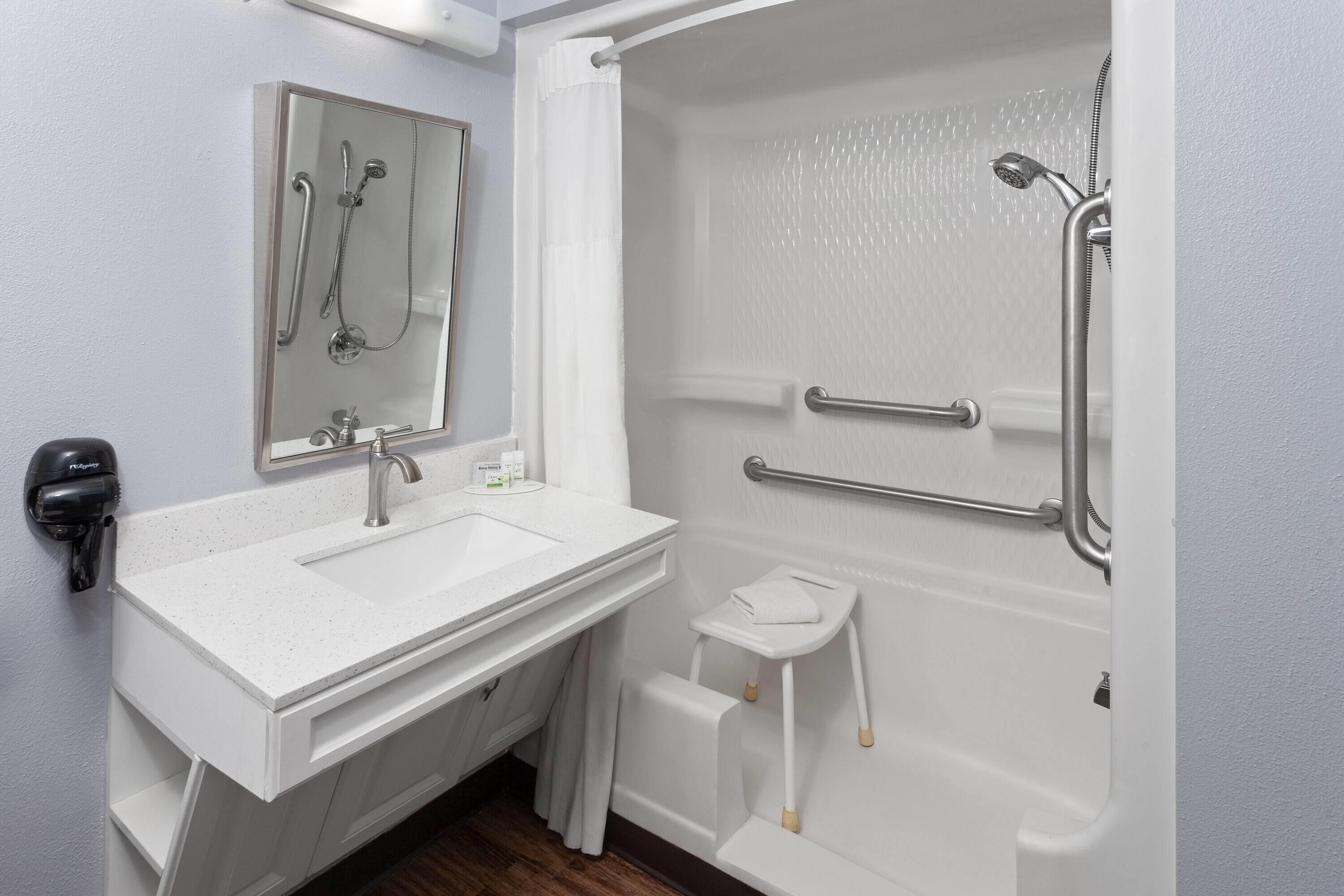 A bathroom with a white sink, mirror, and shower area.