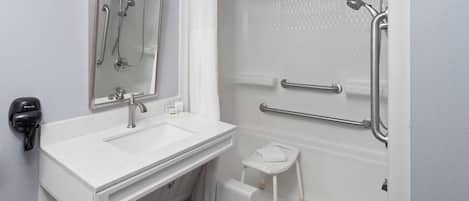 A bathroom with a white sink, mirror, and shower area.