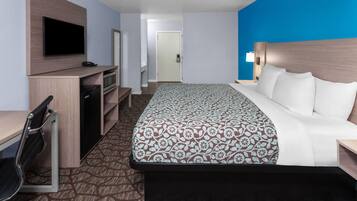 Une chambre d’hôtel équipée d’un lit, d’un bureau, d’une télévision et d’un four à micro-ondes.