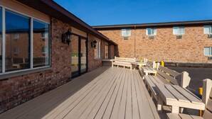 Un espace extérieur abrité, doté de bancs en bois et d’un bâtiment en briques avec des fenêtres.