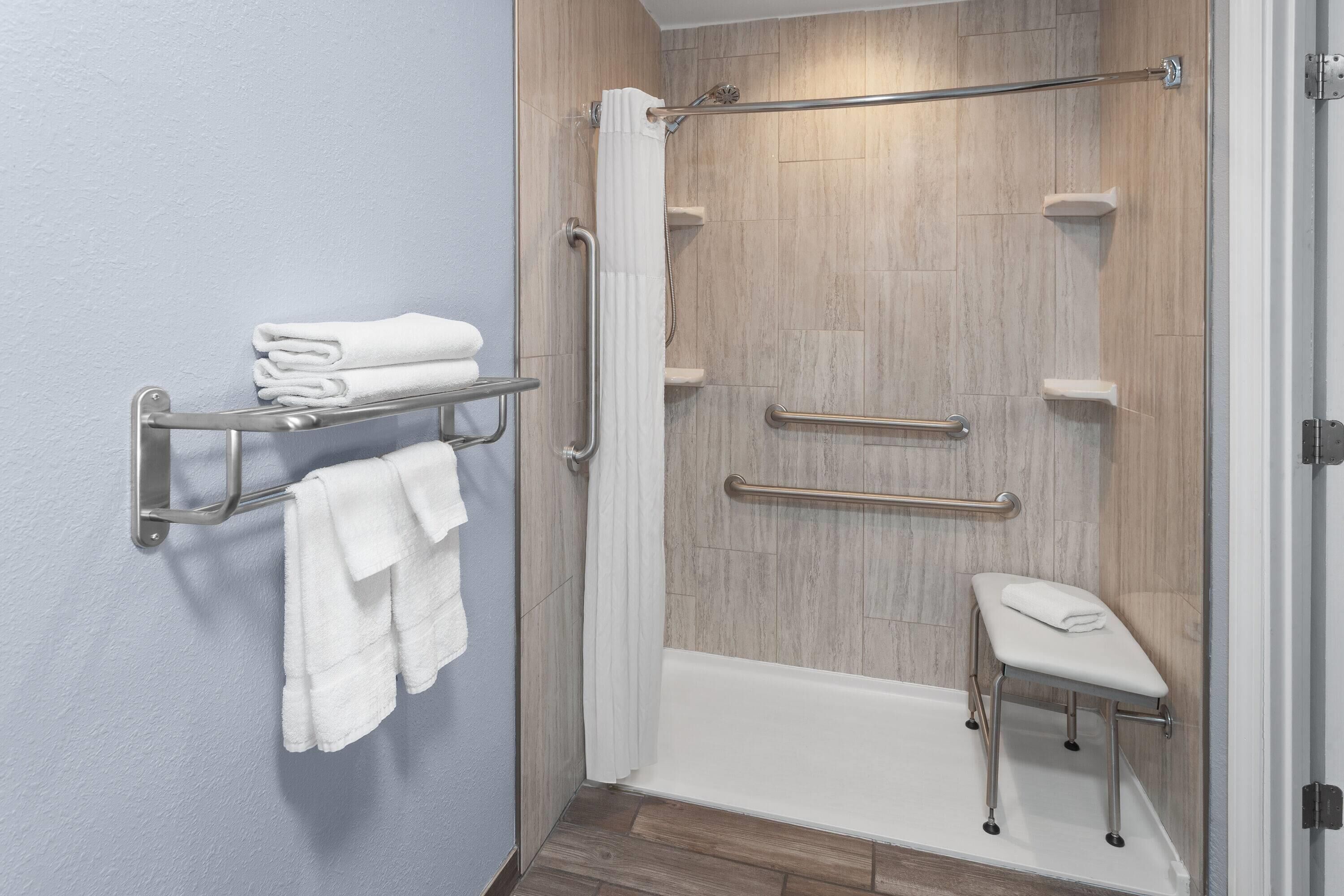Une salle de bain moderne équipée d’une douche, d’un porte-serviettes et d’un banc.