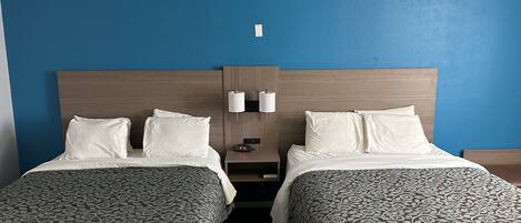 Une chambre d’hôtel avec deux lits, une table de chevet avec une lampe et une horloge murale.