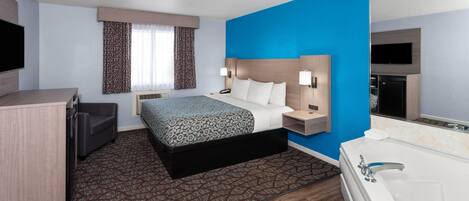 A hotel room with a bed, bedside tables, a desk, a TV, a bathroom with a bathtub, and a window with curtains.