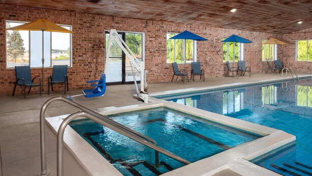 Une piscine intérieure avec un mur en briques, des chaises bleues et des parasols.
