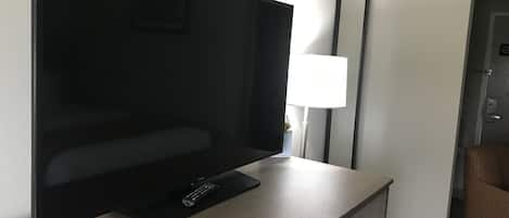 Un televisor de pantalla plana sobre un mueble de televisión de madera en una habitación de hotel.