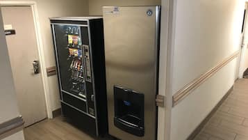Un pasillo con una máquina expendedora y un refrigerador.