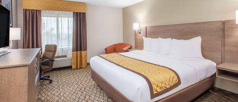 A hotel room with a large bed, a desk, a chair, and a television.