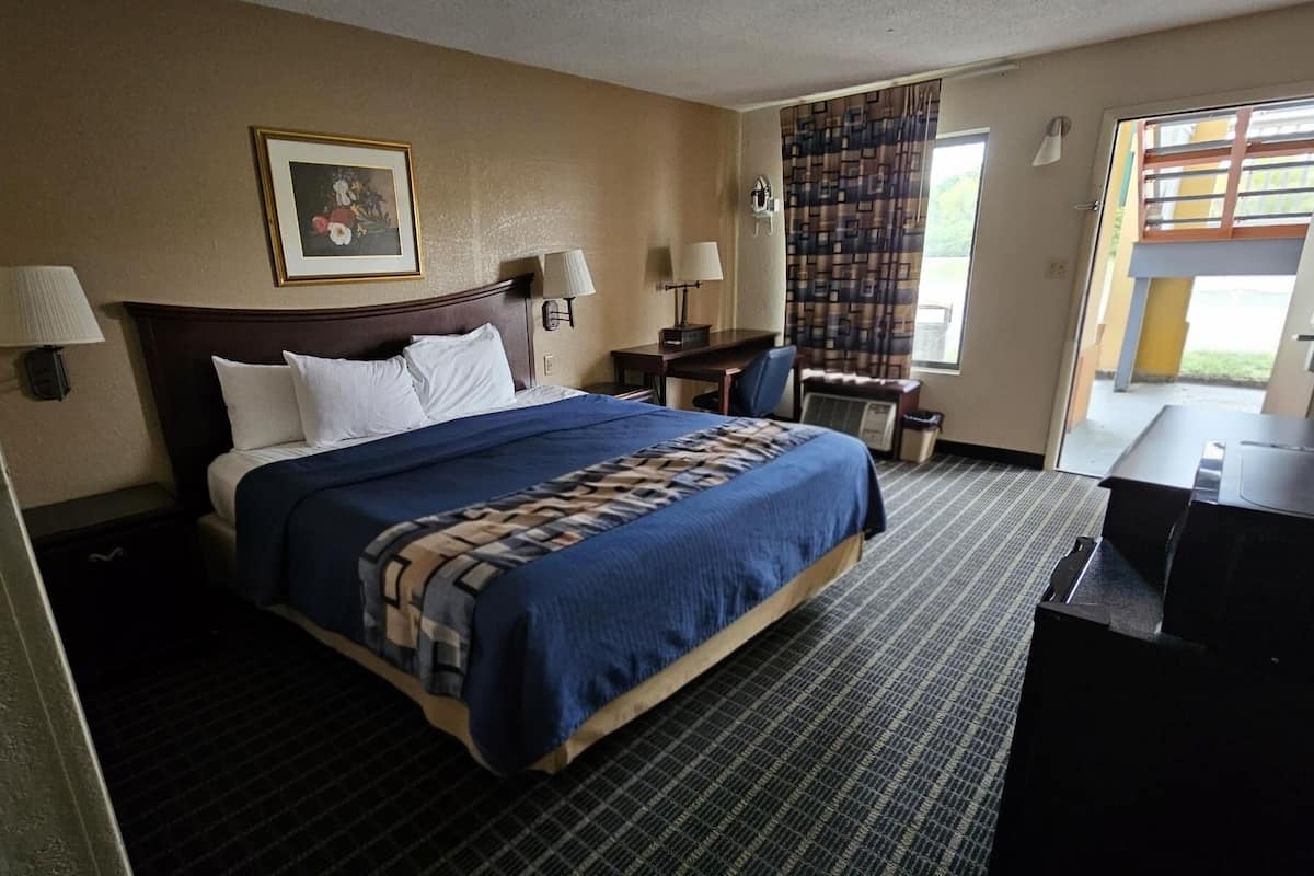 Une chambre d’hôtel avec un grand lit, un bureau, une chaise et une fenêtre avec des rideaux.