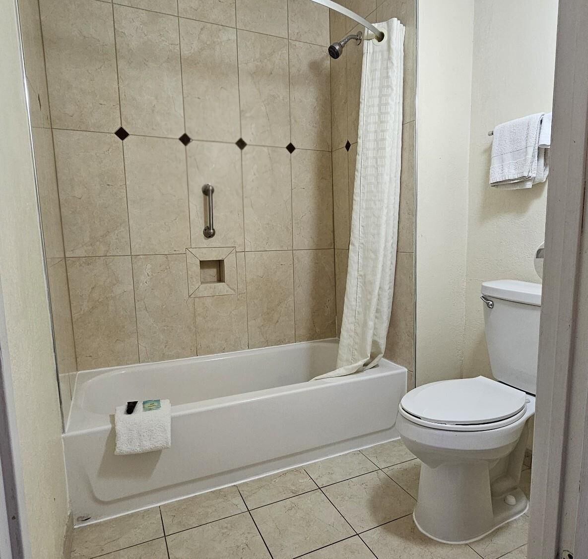 Un baño con bañera, inodoro y cortina de ducha.