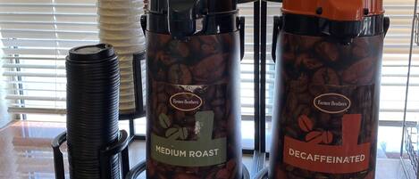 Two coffee machines labeled 'Medium Roast' and 'Decaffeinated' by Farmer Brothers, with coffee pods and a waffle iron on a countertop.