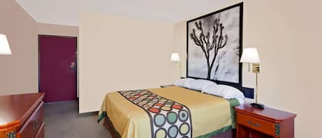 A hotel room with a bed, a nightstand, a dresser, and a door.