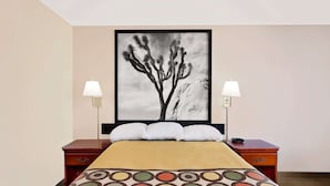 A hotel room with a bed, two bedside tables, a large framed artwork on the wall, and two wall-mounted lamps. - Super 8 by Wyndham Yucca Val/Joshua Tree Nat Pk Area (Yucca Valley)