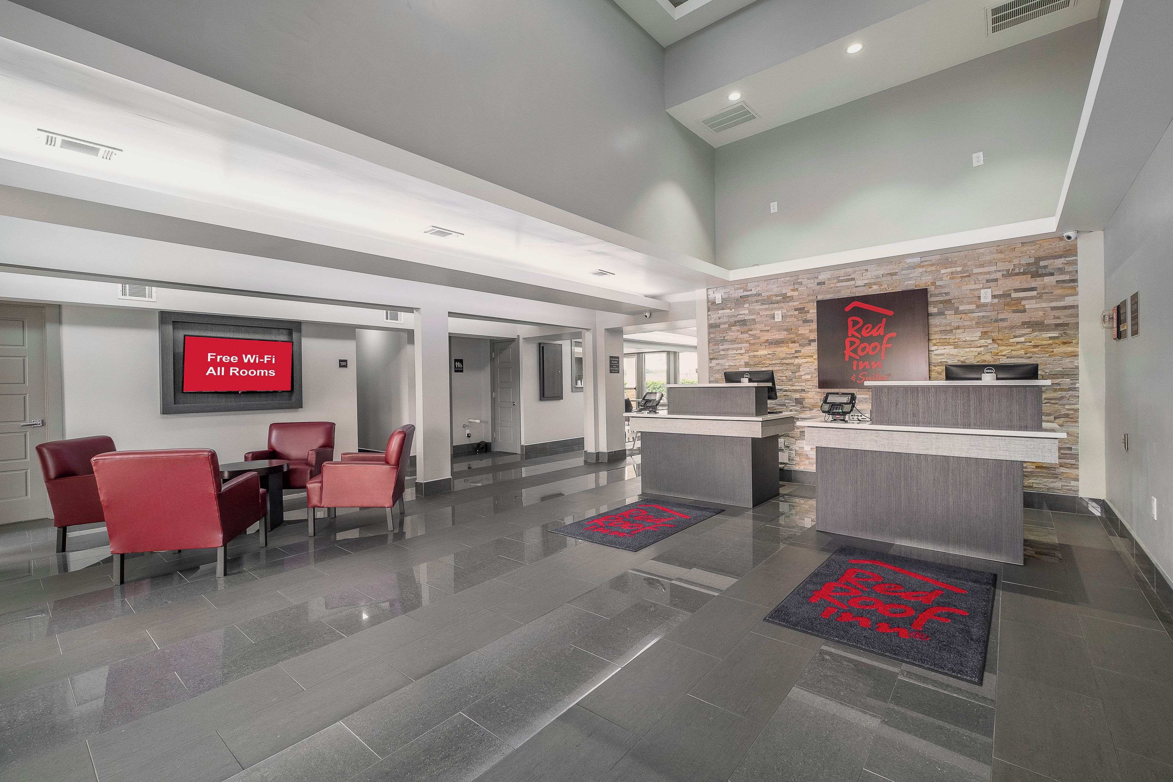 Zona de recepción de hotel con diseño moderno, que incluye un mostrador de recepción, área de estar y un cartel que indica disponibilidad de Wi-Fi gratuito.