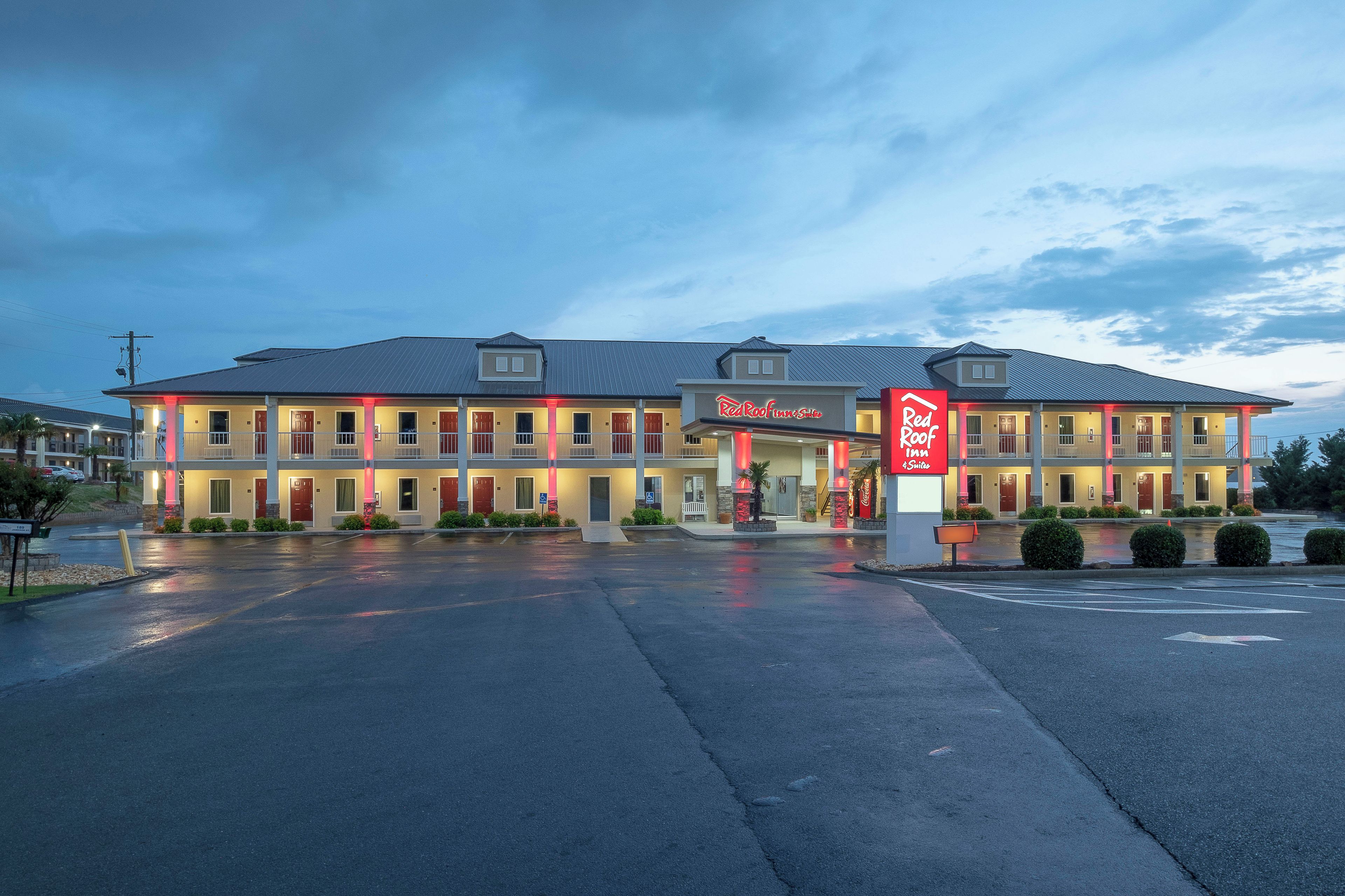 Un Red Roof Inn & Suites con una estructura de dos pisos, un área de estacionamiento techada y un letrero de Coca-Cola.
