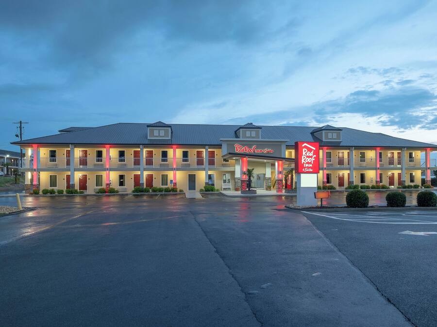 Ett Red Roof Inn & Suites med en tvåvåningsbyggnad, ett takförsett parkeringsområde och en Coca-Cola-skylt.