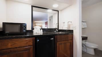 A modern bathroom with a built-in microwave, a sink, and a toilet.