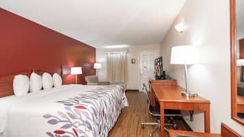 Habitació d'hotel amb llit, escriptori, cadira i televisió.