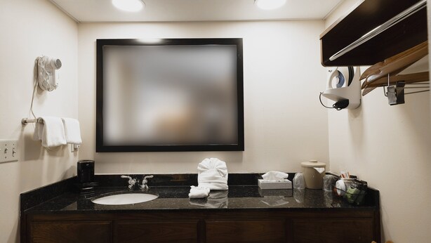 A bathroom with a large mirror, a sink, a towel rack, and a coffee machine.