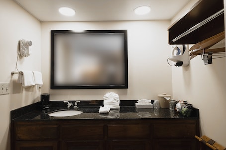 A bathroom with a large mirror, a sink, a towel rack, and a coffee machine.