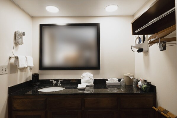 A bathroom with a large mirror, a sink, a towel rack, and a coffee machine. - Red Roof Inn & Suites Calhoun (Calhoun)