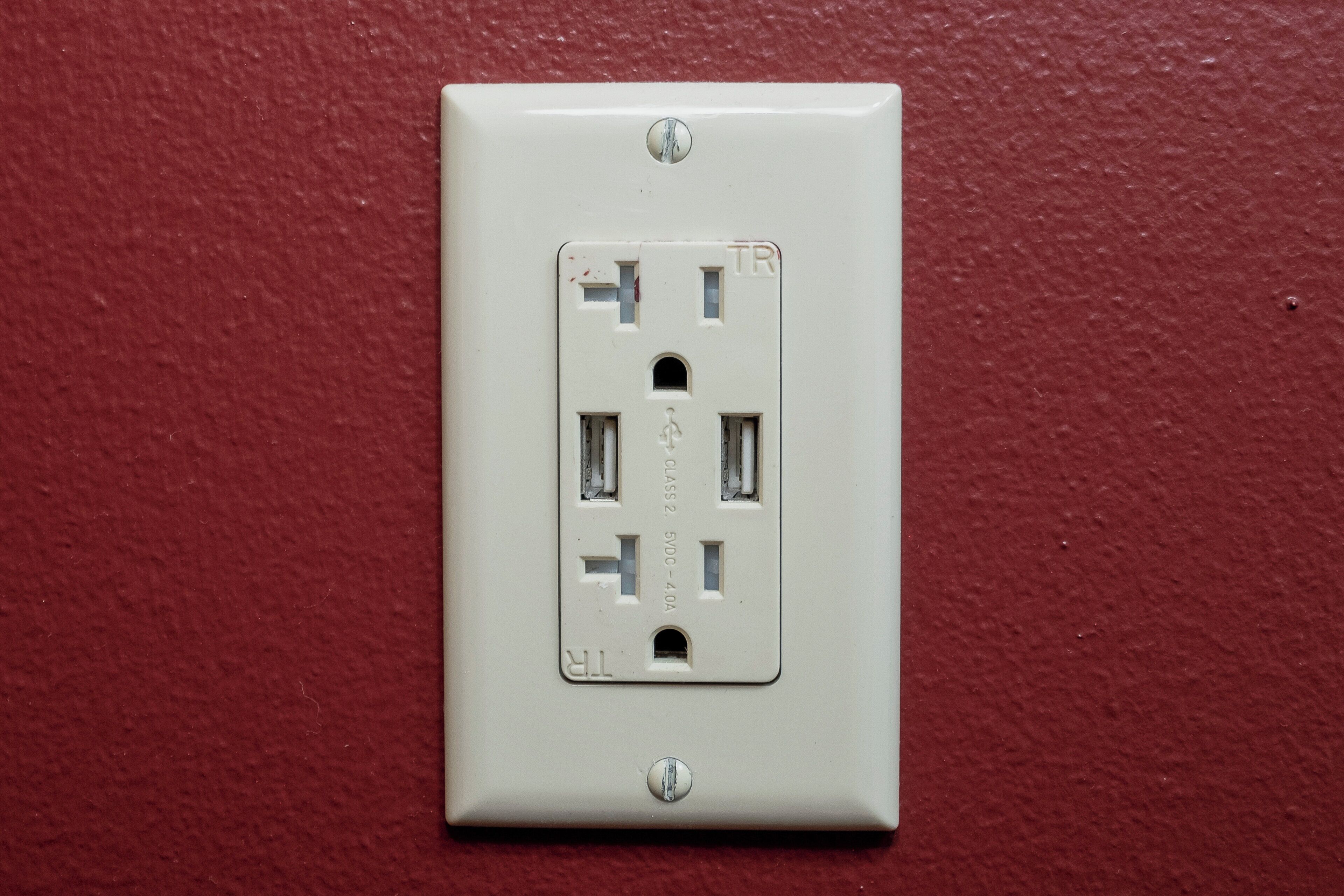 A white electrical outlet on a red wall.