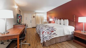 A hotel room with a bed, desk, chair, and lamps.
