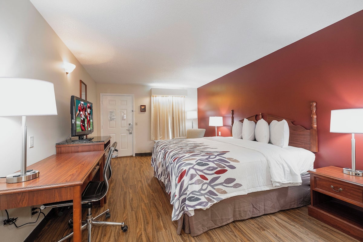 Ein Hotelzimmer mit Bett, Schreibtisch, Stuhl und Lampen.