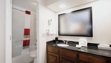 A bathroom with a shower curtain, a toilet, a sink with a mirror above it, and a towel on the counter.