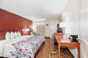 Una habitación de hotel con una cama, un escritorio, una silla, un televisor y una cafetera.