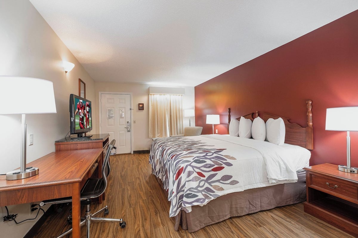 Ein Hotelzimmer mit Bett, Schreibtisch, Stuhl und Fernseher.