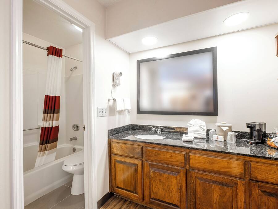 Een badkamer met douche, toilet, wastafel met spiegel en een koffiezetapparaat.
