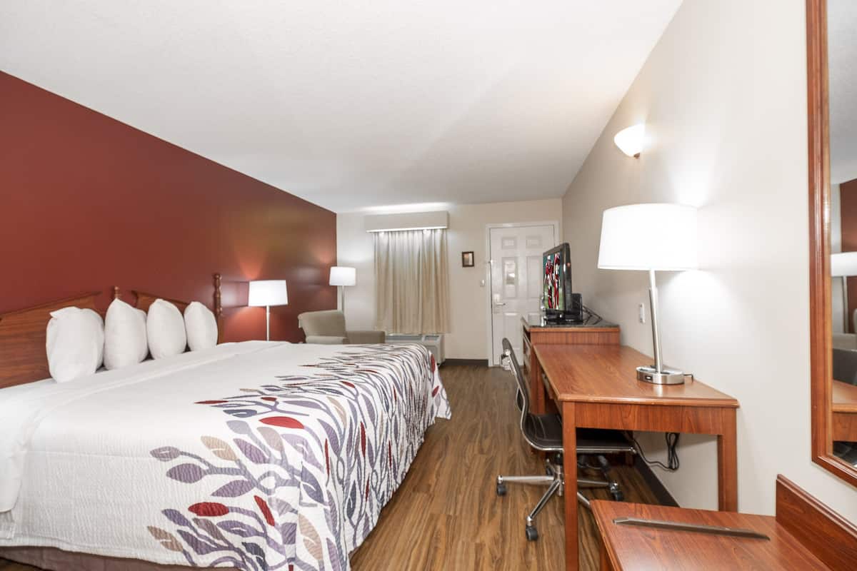 Ein Hotelzimmer mit einem großen Bett, einem Schreibtisch, einem Stuhl und einem Spiegel.