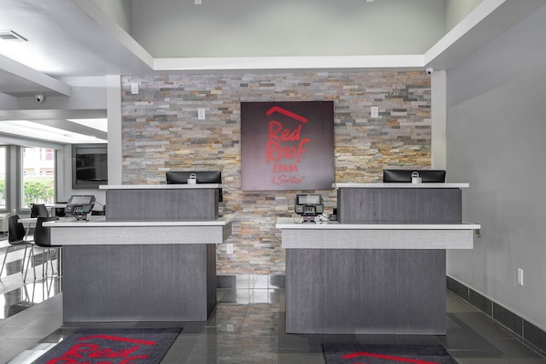 A reception area with two counters, a stone wall, and a Red Roof Inn sign.