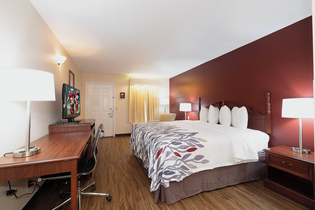 Habitación de hotel con cama, escritorio, silla y lámparas.