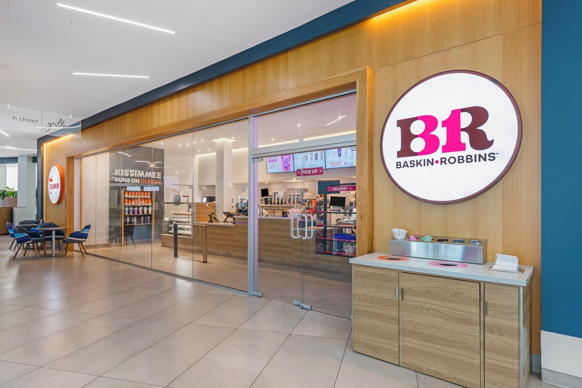A Baskin Robbins store with a modern interior, a counter, and a seating area with chairs. - Holiday Inn Resort Kissimmee by the Parks by IHG (Kissimmee)