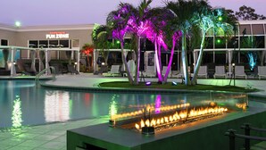 A pool area with a fire feature, lounge chairs, and a building labeled "Chuck E Cheese Fun Zone" in the background. - Holiday Inn Resort Kissimmee by the Parks by IHG (Kissimmee)