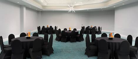 A conference room with round tables, black chairs, and a blue carpet.