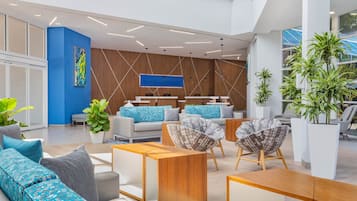 A modern lobby with a blue accent wall, a large abstract painting, and a seating area with sofas and chairs.